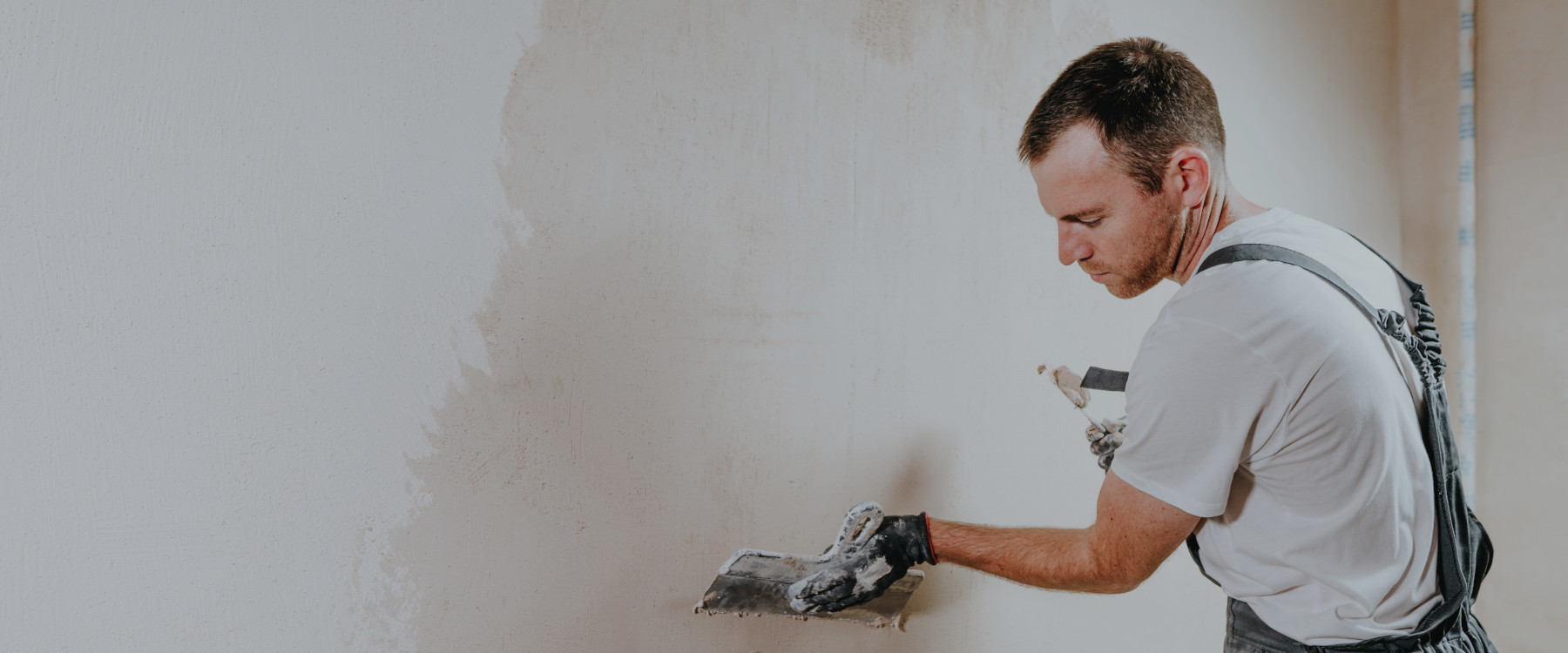 Hausmeister beim Verputzen einer Wand